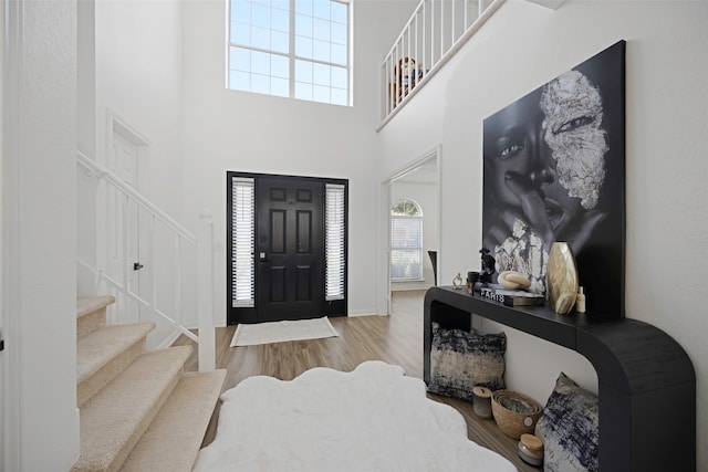 foyer entrance featuring light wood-type flooring and a towering ceiling