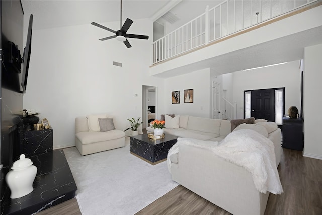 living room with hardwood / wood-style flooring, ceiling fan, and high vaulted ceiling