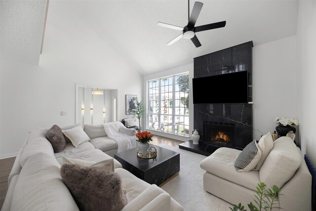 living room featuring high vaulted ceiling, ceiling fan, and a fireplace