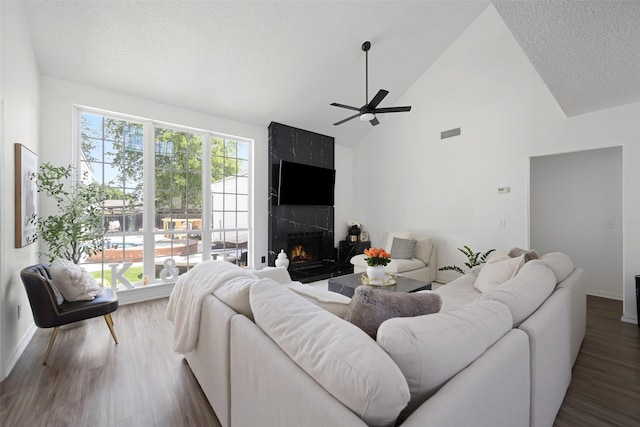 living room featuring plenty of natural light, a large fireplace, ceiling fan, and high vaulted ceiling