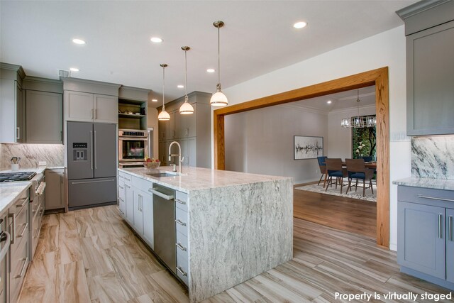 kitchen with light stone countertops, sink, stainless steel oven, hanging light fixtures, and backsplash