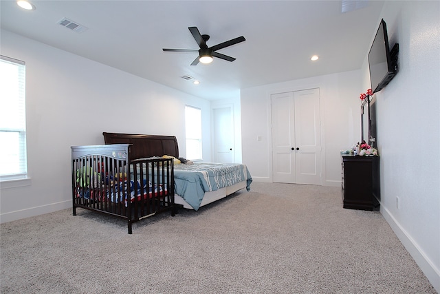 carpeted bedroom featuring multiple windows, ceiling fan, and a closet