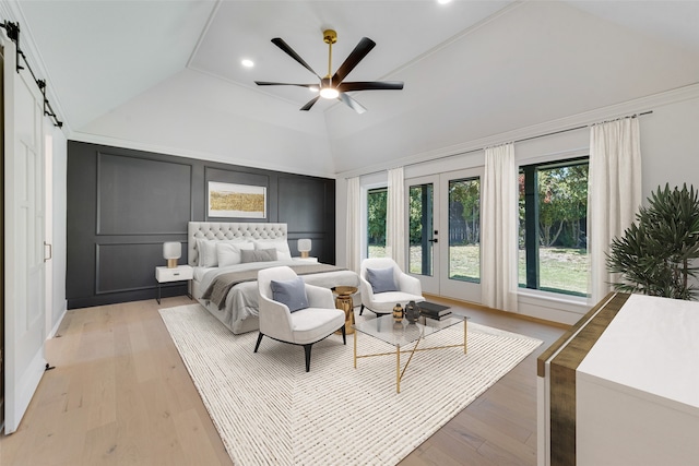 bedroom featuring ceiling fan, vaulted ceiling, light wood-type flooring, and a barn door