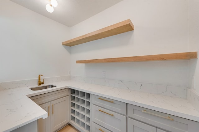 kitchen featuring gray cabinetry, light stone countertops, and sink