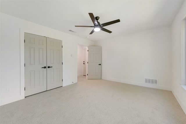 unfurnished bedroom with ceiling fan, light colored carpet, and a closet