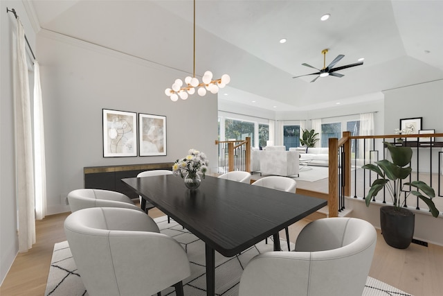 dining space with light wood-type flooring, ceiling fan with notable chandelier, and vaulted ceiling