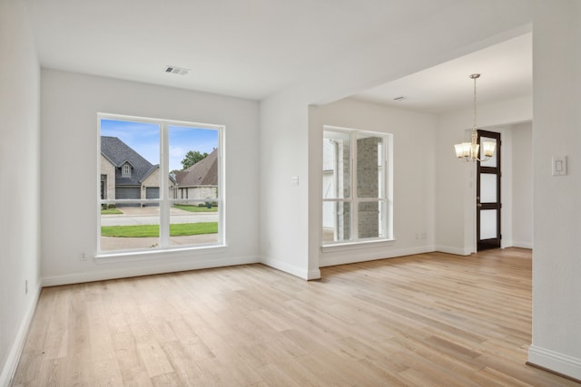 spare room featuring light hardwood / wood-style flooring and a chandelier