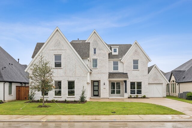 view of front facade with a front lawn, brick siding, roof with shingles, concrete driveway, and fence