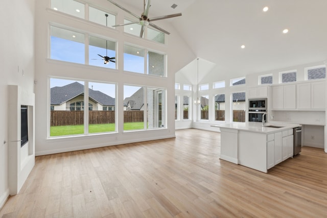 kitchen with stainless steel appliances, white cabinetry, high vaulted ceiling, a ceiling fan, and open floor plan