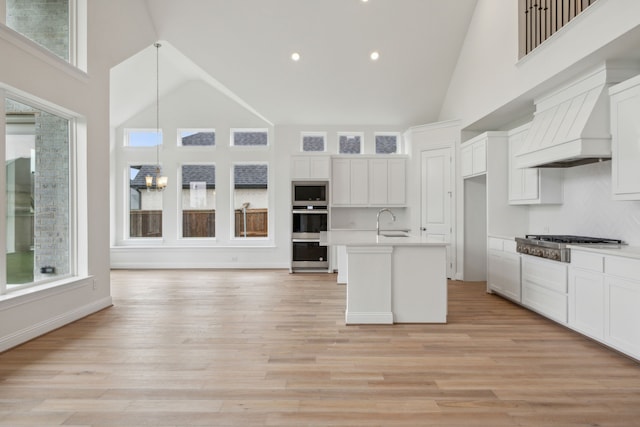 kitchen with white cabinetry, a towering ceiling, decorative light fixtures, and appliances with stainless steel finishes