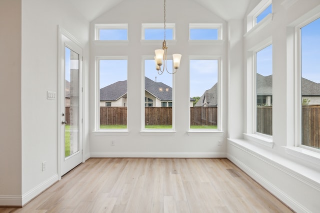 unfurnished sunroom with a chandelier, vaulted ceiling, and a healthy amount of sunlight