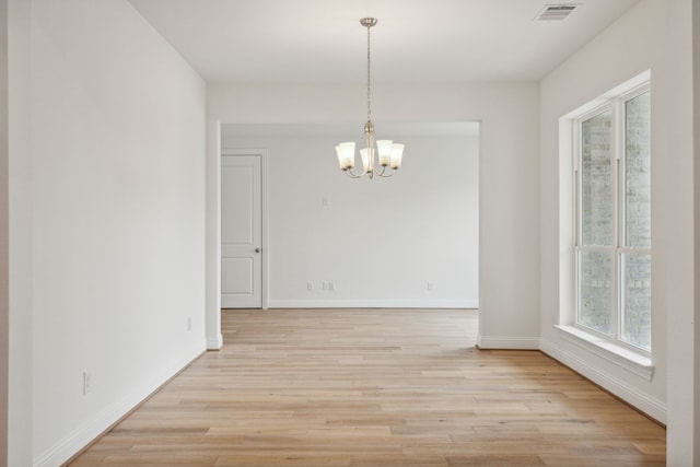 unfurnished room with light hardwood / wood-style floors and an inviting chandelier