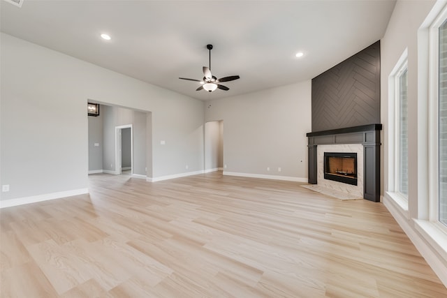 unfurnished living room with ceiling fan, light hardwood / wood-style floors, and a tile fireplace