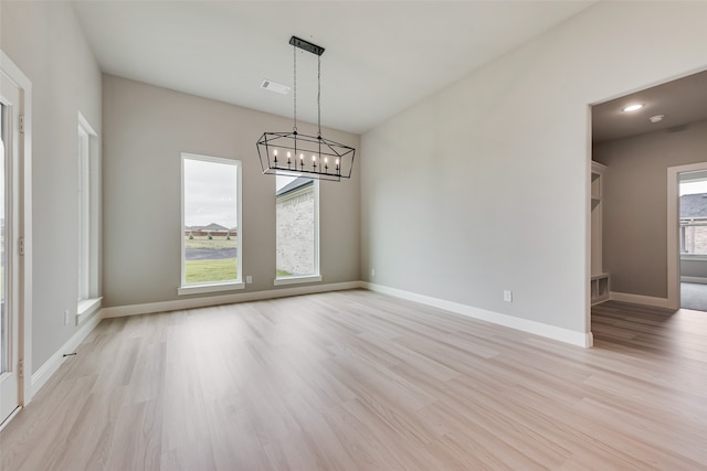 unfurnished room with a notable chandelier and light wood-type flooring