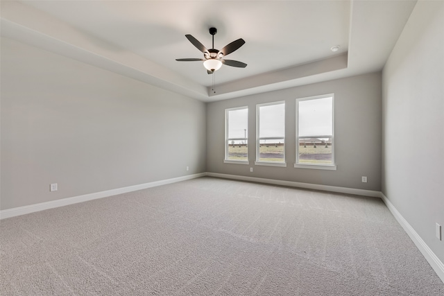 spare room featuring a tray ceiling, ceiling fan, and light colored carpet