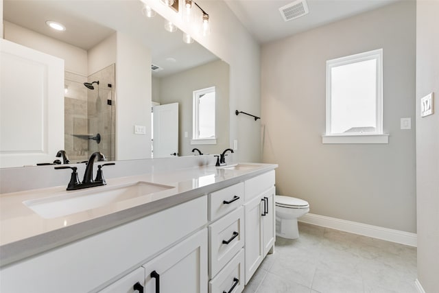 bathroom with tile patterned floors, tiled shower, vanity, and toilet