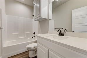 full bathroom with vanity, toilet, washtub / shower combination, and hardwood / wood-style flooring