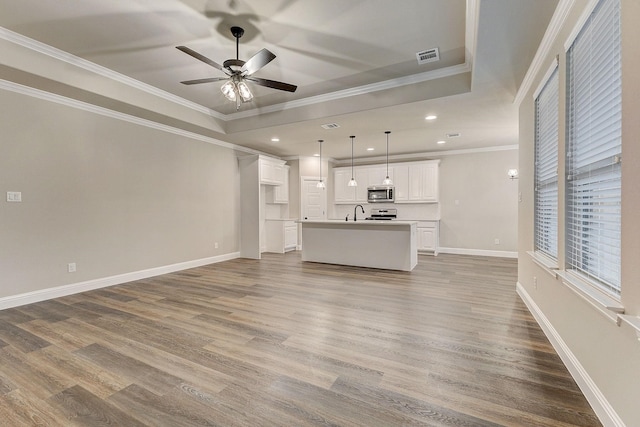 unfurnished living room featuring sink, ceiling fan, hardwood / wood-style flooring, and crown molding