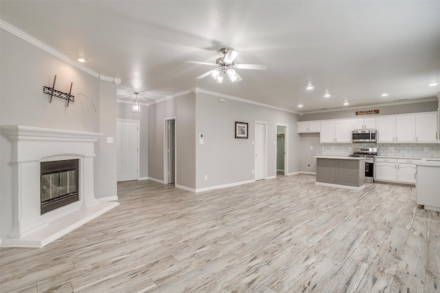 kitchen with appliances with stainless steel finishes, decorative backsplash, white cabinetry, light wood-type flooring, and ceiling fan