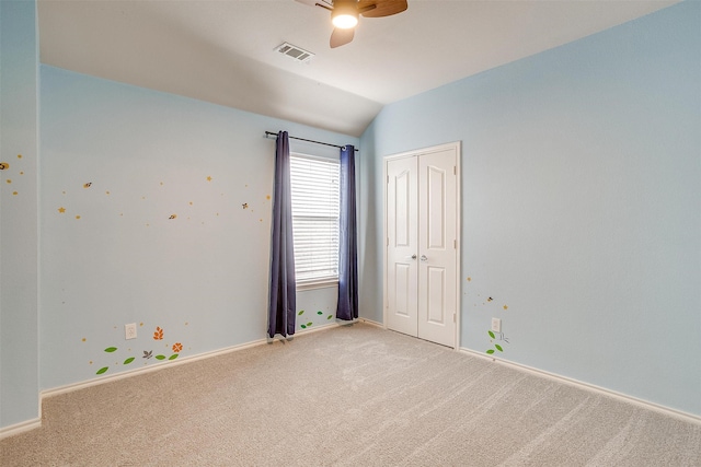 carpeted spare room featuring ceiling fan and vaulted ceiling