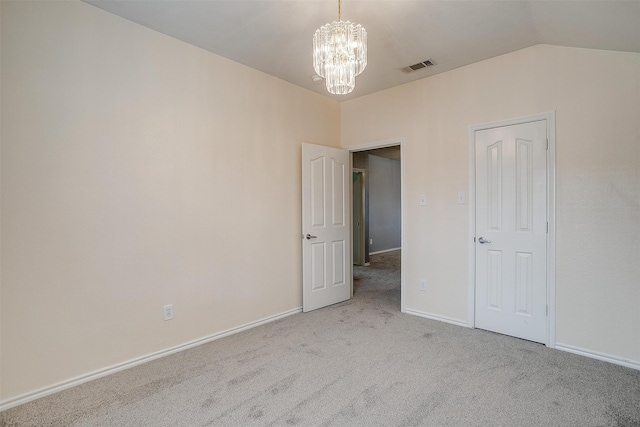 interior space with vaulted ceiling, an inviting chandelier, and light carpet