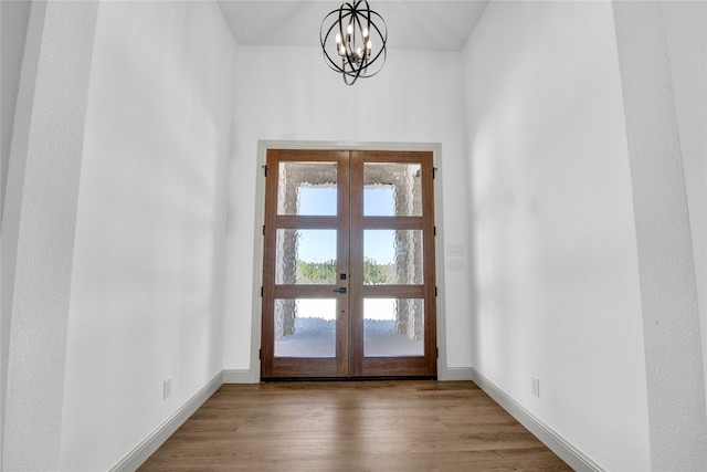 entryway with french doors, a notable chandelier, and light wood-type flooring