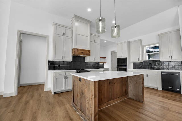 kitchen with a kitchen island, light wood-type flooring, sink, pendant lighting, and appliances with stainless steel finishes