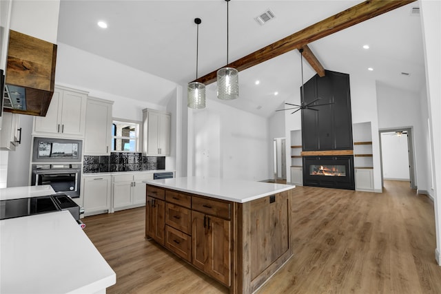 kitchen with a kitchen island, high vaulted ceiling, ceiling fan, and light hardwood / wood-style flooring