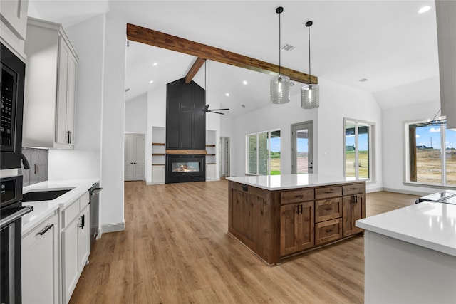 kitchen featuring white cabinets, beamed ceiling, light wood-type flooring, and a center island