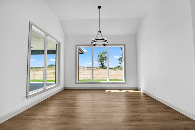 unfurnished dining area featuring vaulted ceiling, a notable chandelier, and dark wood-type flooring