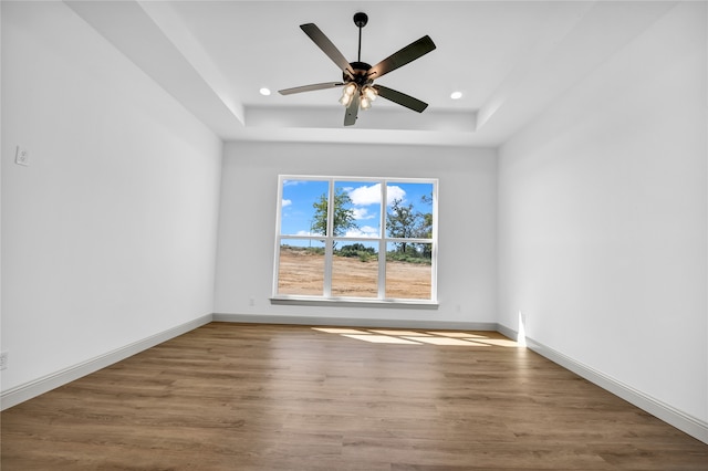 spare room with ceiling fan, a tray ceiling, and hardwood / wood-style floors