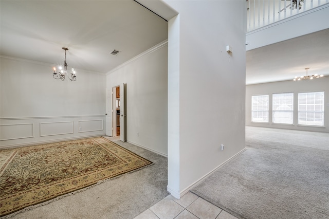 foyer entrance featuring ornamental molding, light colored carpet, and a chandelier