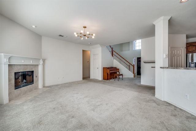 unfurnished living room with light carpet, a notable chandelier, and a tile fireplace