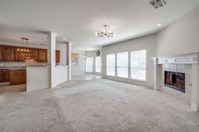 unfurnished living room featuring a notable chandelier, a fireplace, and light tile patterned floors