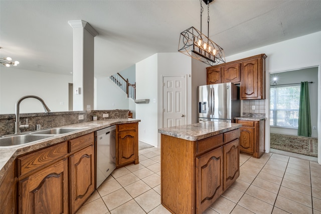 kitchen with sink, a kitchen island, an inviting chandelier, stainless steel appliances, and decorative light fixtures