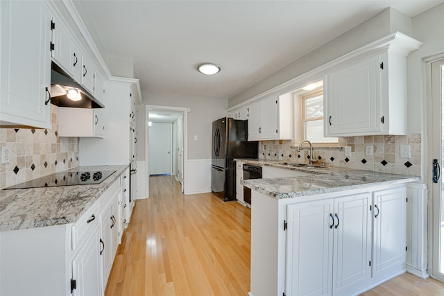 kitchen featuring sink, light hardwood / wood-style flooring, black appliances, white cabinetry, and light stone countertops