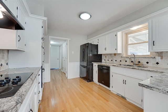 kitchen featuring light wood-type flooring, black appliances, tasteful backsplash, and white cabinets