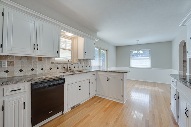 kitchen with sink, backsplash, white cabinetry, black dishwasher, and light wood-type flooring