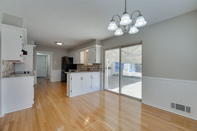 kitchen featuring white cabinets, backsplash, light hardwood / wood-style flooring, decorative light fixtures, and sink