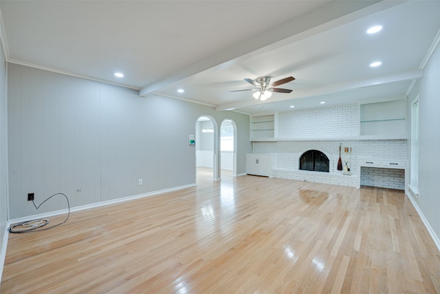 unfurnished living room with a brick fireplace, light wood-type flooring, crown molding, and ceiling fan