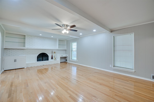 unfurnished living room with light hardwood / wood-style floors, a fireplace, crown molding, beam ceiling, and ceiling fan