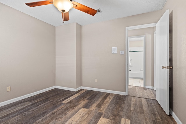 unfurnished room with a textured ceiling, ceiling fan, and dark wood-type flooring