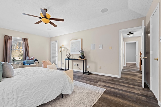 bedroom with vaulted ceiling, dark wood-type flooring, a closet, a textured ceiling, and ceiling fan