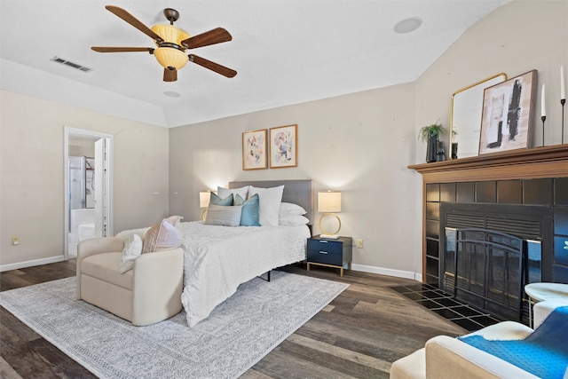 bedroom with connected bathroom, ceiling fan, a fireplace, and dark wood-type flooring