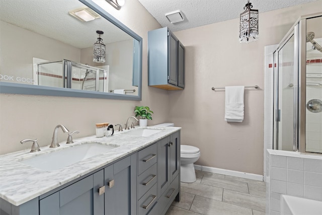 bathroom featuring tile patterned flooring, a textured ceiling, a shower with shower door, vanity, and toilet