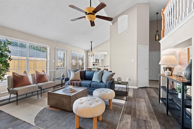 living room featuring a textured ceiling, ceiling fan with notable chandelier, dark wood-type flooring, and high vaulted ceiling