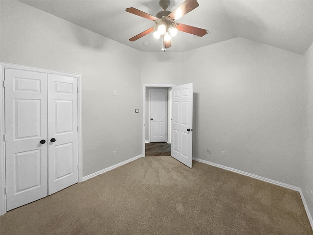 unfurnished bedroom with ceiling fan, carpet flooring, a closet, and vaulted ceiling