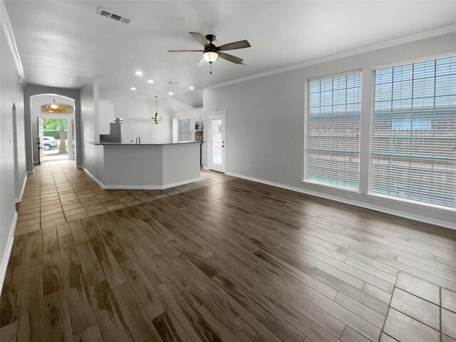 unfurnished living room featuring dark wood-type flooring, ceiling fan, and a healthy amount of sunlight