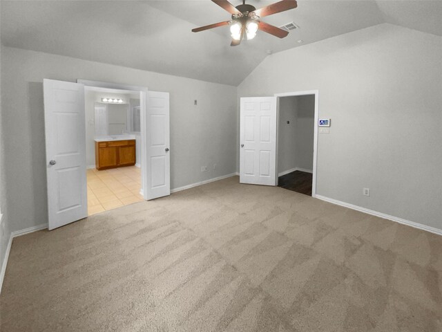 unfurnished bedroom with lofted ceiling, ensuite bath, ceiling fan, and light carpet