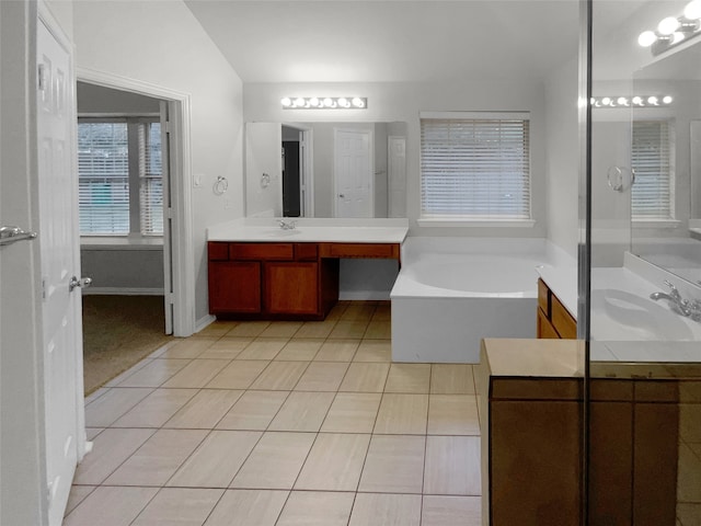 bathroom with vanity, a bathing tub, lofted ceiling, and tile patterned floors